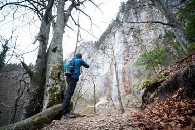 Deneyimli yürüyüşçü takım arkadaşlarıyla şelalenin önünde duruyor.