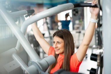 Kol egzersizleri için spor aletleri kullanan güzel bir genç kadın.