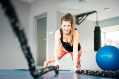 Güzel kadın savaş halatlarını kullanırken kalas yapıyor.