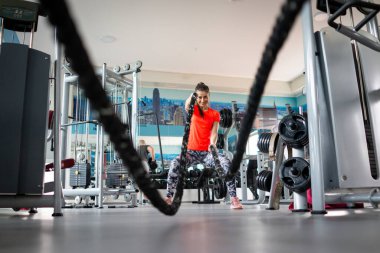 Güzel genç bayan spor salonunda halat kullanıyor.