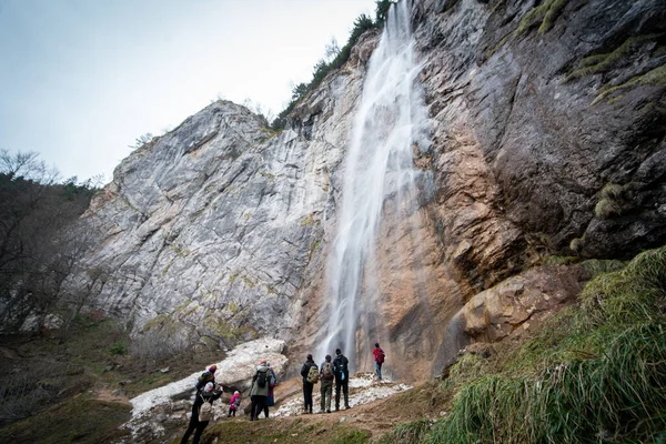 有经验的徒步旅行者和他的队友站在瀑布前 — 图库照片