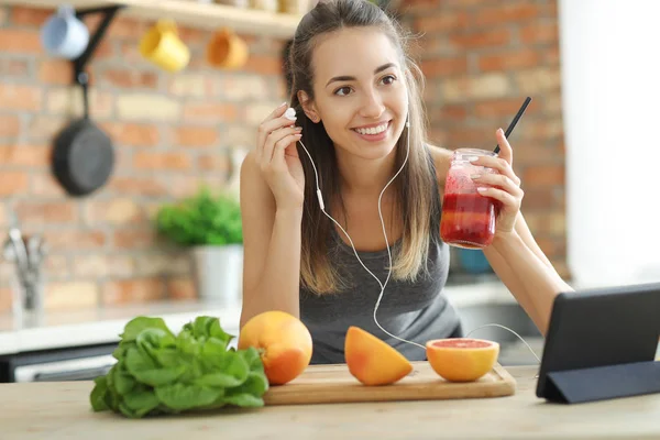 female food blogger with smoothie and earphones at kitchen, healthy food