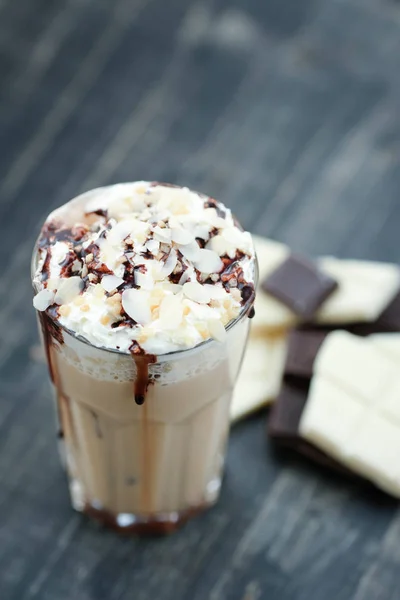 hot sweet coffee in glass, caramel frappe with chocolate topping on wooden table