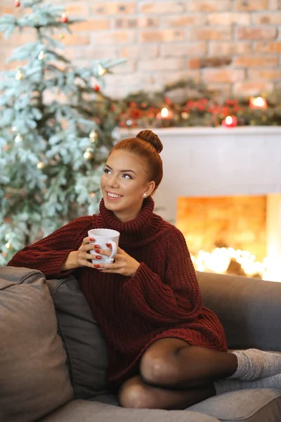 Beautiful woman with cup of tea at home on Christmas Eve