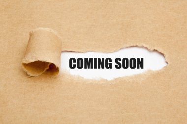 The phrase Coming Soon appearing behind ripped brown paper. Concept about upcoming promising event approaching in near future. clipart