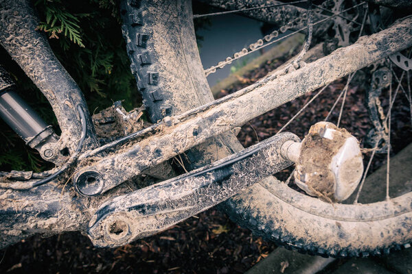 Mountain biking, dirty and broken bicycle closeup. MTB bicycle with mud and sand waiting for cleaning and repairing. Adventure and extreme enduro cycling sport concept.