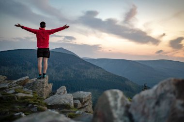 Adam dağ tepe on Sunset kutluyor. Bakarak görünümü ilham verici. Atlet, uzun yürüyüşe çıkan kimse ya da dağcı dağın zirveye ulaştığı trail, kayalık izinde Karkonosze, Polonya ilham verici manzara keyfini çıkarın