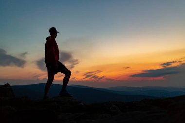 Adam dağ tepe on Sunset kutluyor. Bakarak görünümü ilham verici. Atlet, uzun yürüyüşe çıkan kimse ya da dağcı dağın zirveye ulaştığı trail, kayalık izinde Karkonosze, Polonya ilham verici manzara keyfini çıkarın