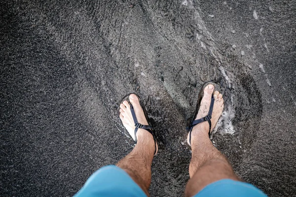 Концепция Баланса Жизни Человек Смотрит Вниз Ноги Сандалии Вулканический Пляж — стоковое фото