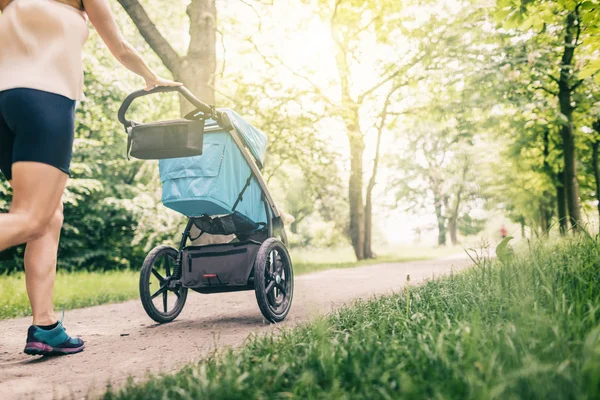 跑步的女人与婴儿推车享受在公园的夏天一天 慢跑或动力行走超级妈妈 活跃的家庭与婴儿跑步 — 图库照片