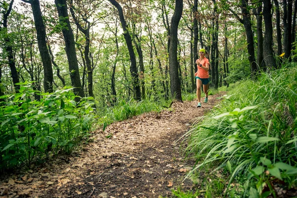 Trail running woman in green forest. Endurance sport training. Female trail runner cross country running. Sport and fitness concept outdoors in nature.