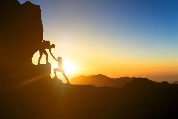 团队合作情侣帮助手信任帮助剪影在山 登山者和女人远足的队伍 在山顶上互相帮助 一起攀登 在大加那利岛上鼓舞人心的日落 — 图库照片