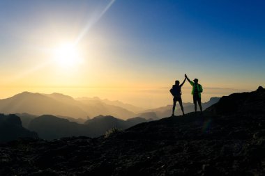 Günbatımı dağlar başarı kutluyor yürüyüşçü çift, silah kadar uzanmış ile başarmak. Genç adam ve kadın, ilham verici güzel görünümü, Gran Canaria Kanarya Adaları manzara.