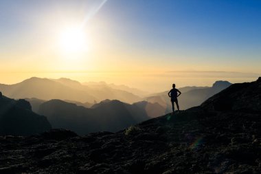 Kadın siluet dağlar, gün batımı ve okyanus hiking. Güzel ilham verici manzaraya, gün batımı ilham verici manzara seyir kadın uzun yürüyüşe çıkan kimse.