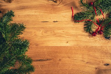Noel arka plan ile kahverengi ahşap masa üzerinde köknar ağacı, kırmızı parlak çanları. Kopya alanı ile üst düz görünüm.