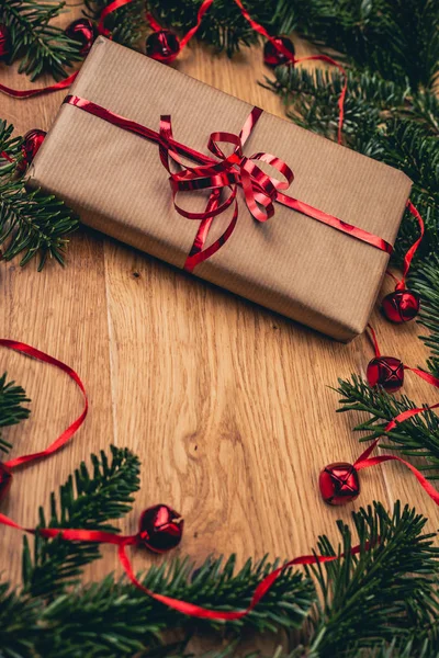 圣诞礼物在木板上 有冷杉树 红色的铃铛 纸礼品盒上的红色丝带 顶部特写镜头视图与复制空间 图库图片