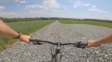Yeşil tarlalar arasında kayalık yolda Enduro dağ bisikleti sürmek. Birinci şahıs bakış açısından bak Pov. 4k titreşim sabitleyici video, Gopro Kahraman 7 siyah.