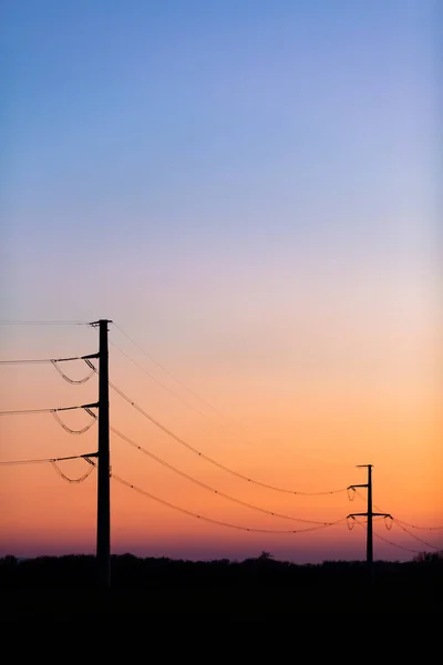 日の出や日没のカラフルな澄んだ空の上の電力線のシルエット 停電の概念 ストック写真