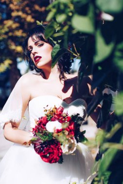 Beyaz gelinlikli güzel gelin dışarıda poz veriyor.