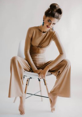 Güzel genç kadın moda bej Üst ve Studio güzel küpe poz 