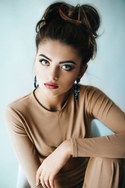 Güzel genç kadın moda bej Üst ve Studio güzel küpe poz 