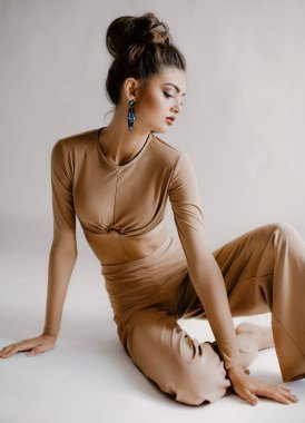 Güzel genç kadın moda bej Üst ve Studio güzel küpe poz 