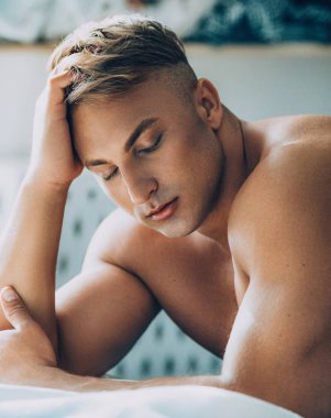 Güçlü sağlıklı yakışıklı atletik erkek yatakta poz portresi