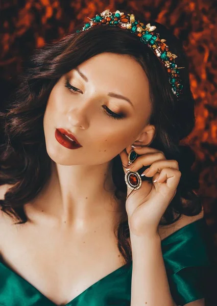 Beautiful young woman in dress and earrings posing in studio