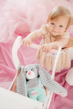 Güzel küçük bir kız bebek arabası ve stüdyoda poz oyuncak ile