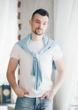 Beyaz t-shirt boğazlı kazak poz içinde şık adam