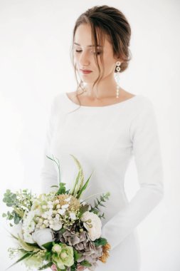Güzel genç gelin çiçekleri ile poz beyaz gelinlik