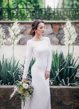 Güzel genç gelin çiçekleri ile poz beyaz gelinlik