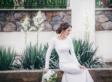 Güzel genç gelin çiçekleri ile poz beyaz gelinlik