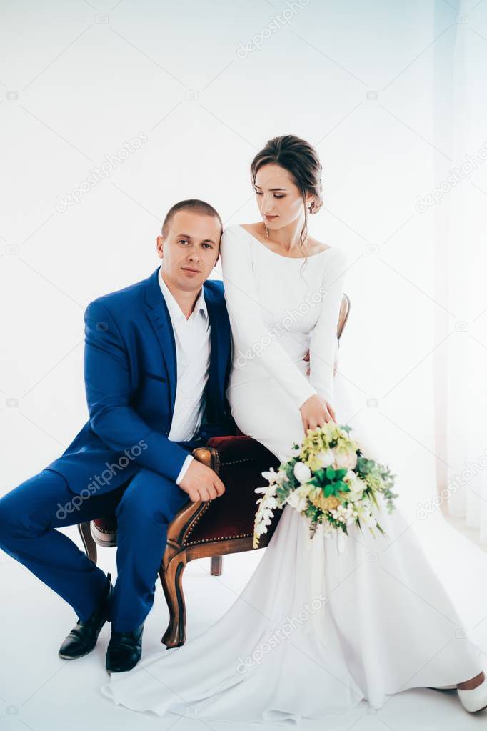 Beautiful and young bride and groom posing at room  