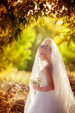 Beyaz gelinlikli güzel gelin dışarıda poz veriyor.