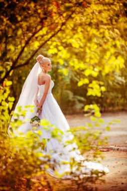 Beyaz gelinlikli güzel gelin dışarıda poz veriyor.