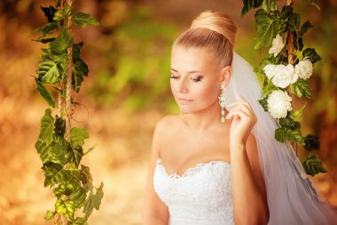 Beyaz gelinlikli güzel gelin dışarıda poz veriyor.