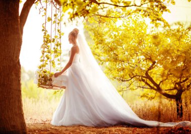 Beyaz gelinlikli güzel gelin dışarıda poz veriyor.