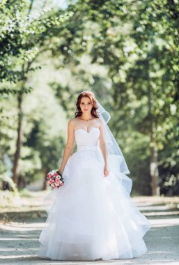 Beyaz gelinlikli güzel gelin dışarıda poz veriyor.