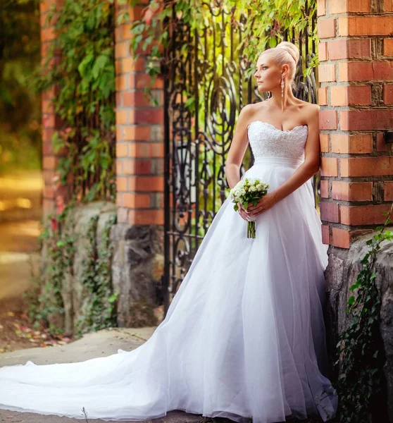 Beyaz gelinlikli güzel gelin dışarıda poz veriyor.