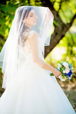 Parkta poz beyaz gelinlikle güzel genç gelin  