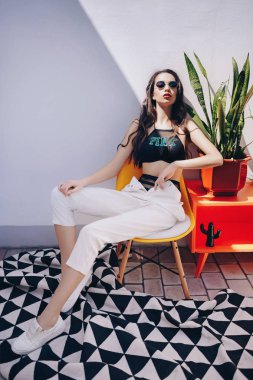 Güzel genç kadın üst ve beyaz pantolonuyla poz