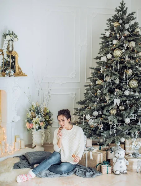 Beautiful woman near Christmas tree posing with drink at home