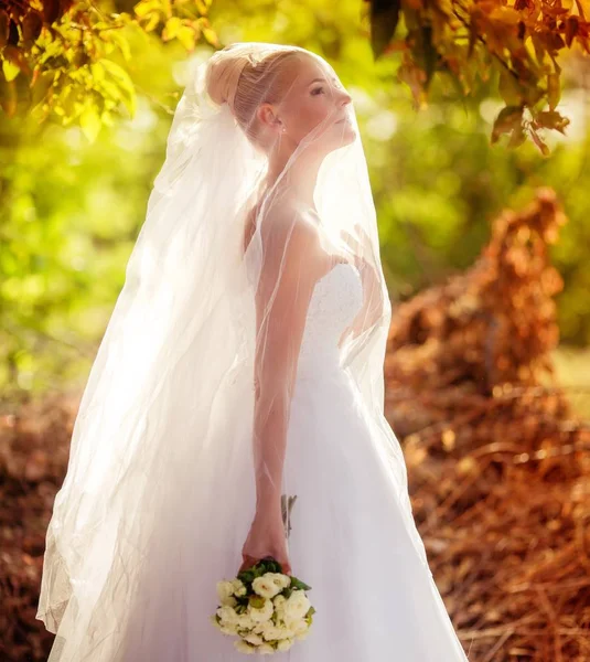 Parkta poz beyaz gelinlikle güzel genç gelin