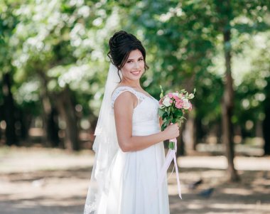 Parkta poz beyaz gelinlikle güzel genç gelin 