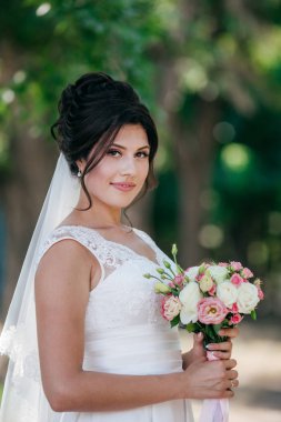 Parkta poz beyaz gelinlikle güzel genç gelin 