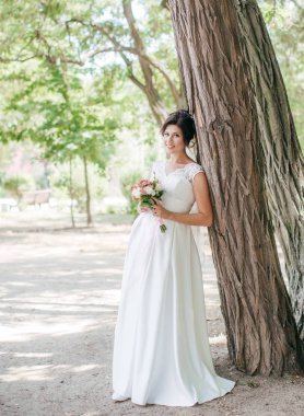 Parkta poz beyaz gelinlikle güzel genç gelin 