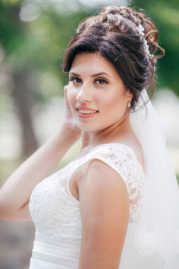 Parkta poz beyaz gelinlikle güzel genç gelin 