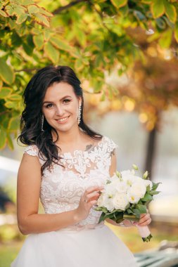 Parkta poz beyaz gelinlikle güzel genç gelin