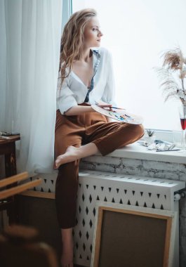 Odada poz veren genç ve güzel sanatçı kadın